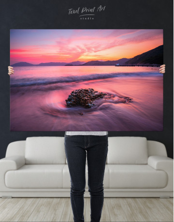 Rock in a Wavy Sea under an Orange and Pink Sky at Sunset Canvas Wall Art - image 1